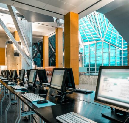 A row of desktop computers with keyboards and mice set up on tables in a modern building with tall ceilings and large windows, maintained at optimal conditions by a Computer room air handling unit by CITEC.