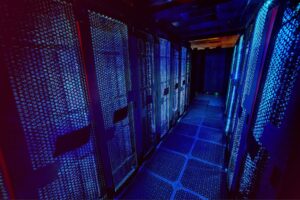 A dimly lit CITEC server room with rows of black server racks illuminated by blue and purple LED lights.